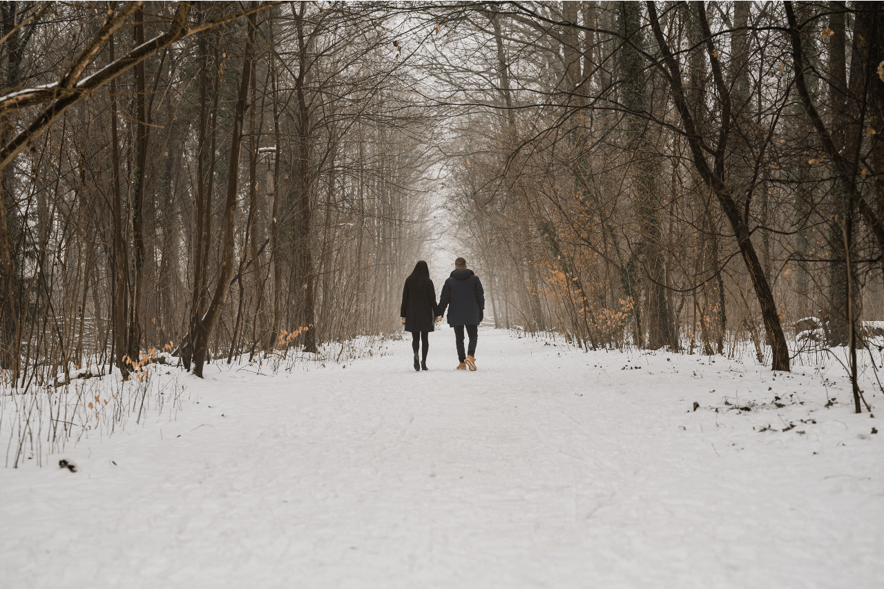 a couple holding hands walking in the snow