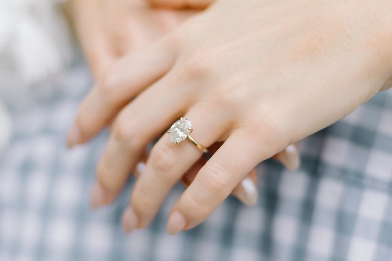 a lady’s hand wearing a solitaire ring with prong setting
