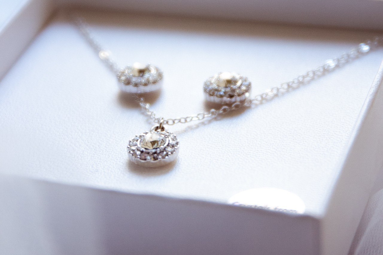 A pair of diamond stud earrings with a matching pendant in a gift box.