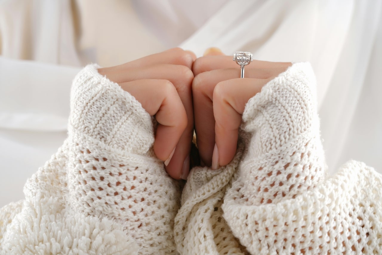 A side view of a woman’s platinum hidden halo engagement ring.