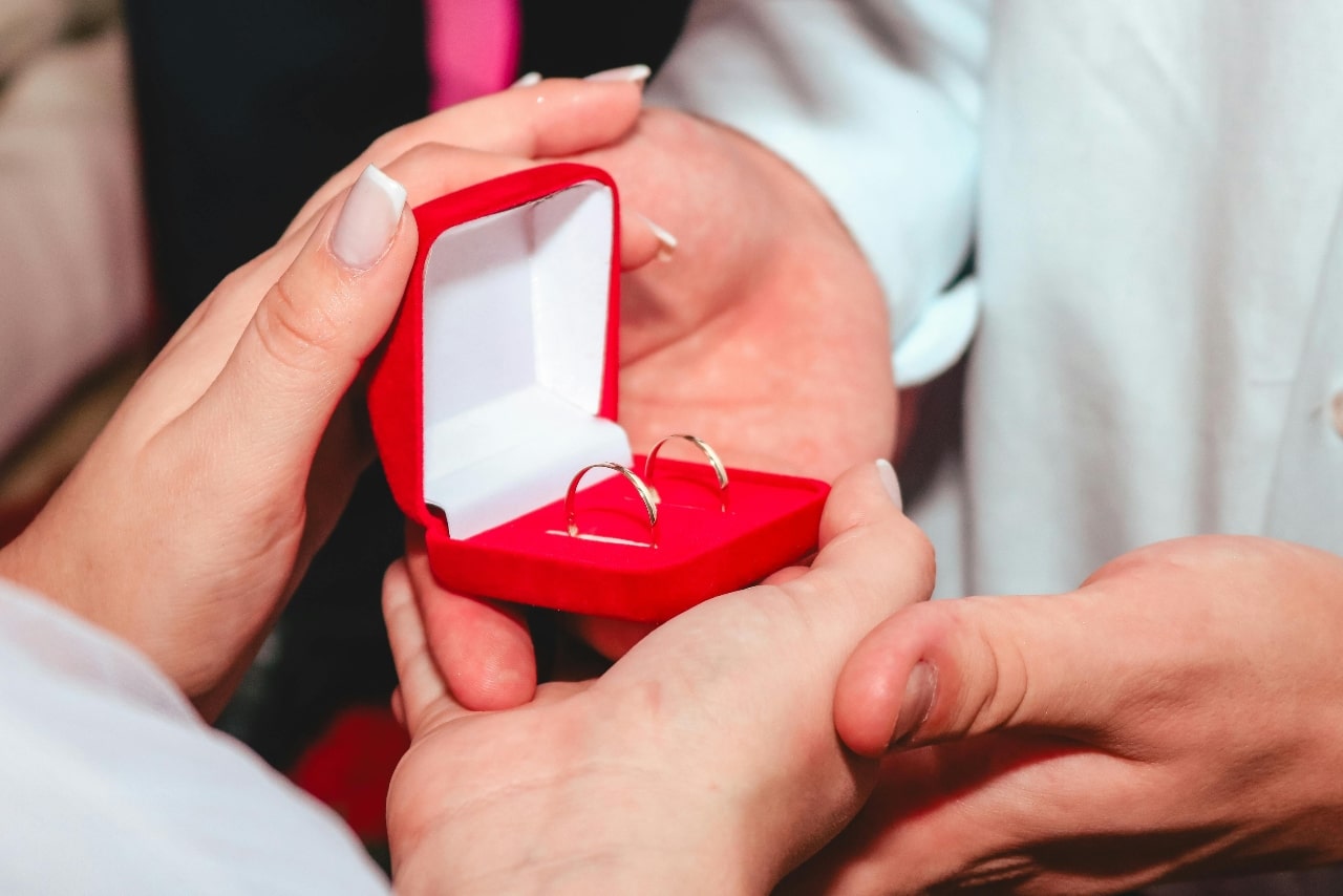 A close-up of a jeweler’s hands as they show a pair of earrings to a customer.