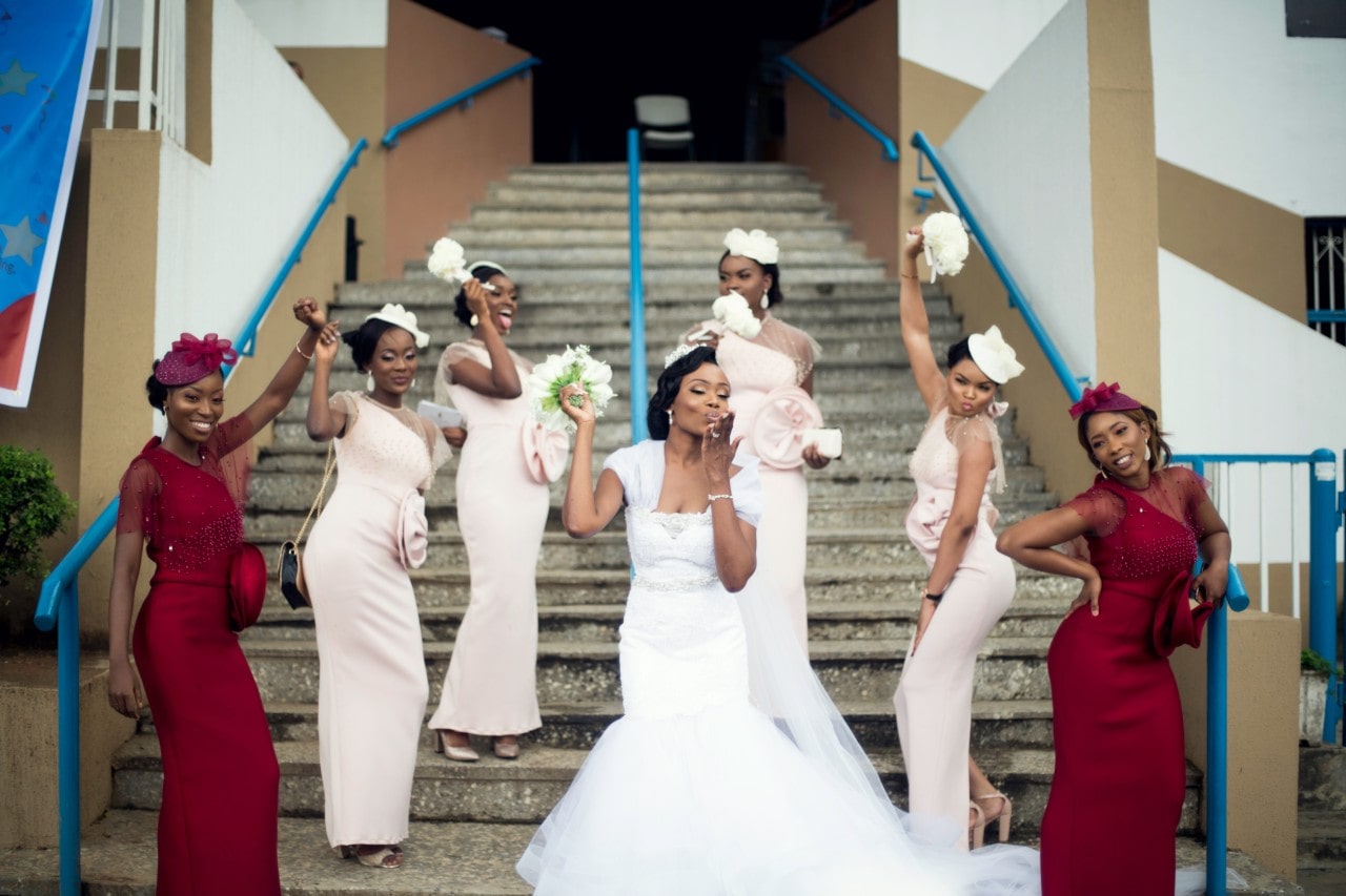 Bride, maids of honor, and bride’s maids outside of a local building, posing on their steps