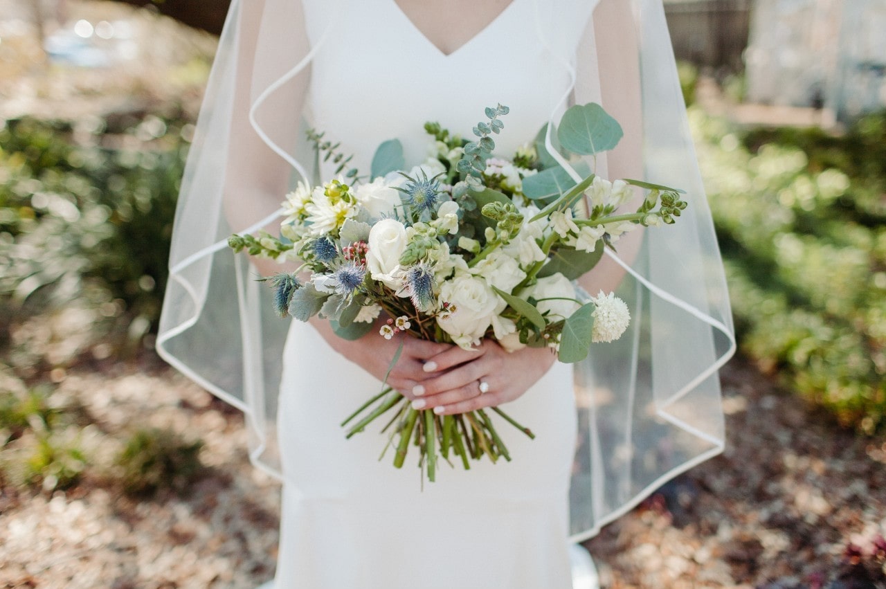 A bride holding her bouquet wears her engagement ring.