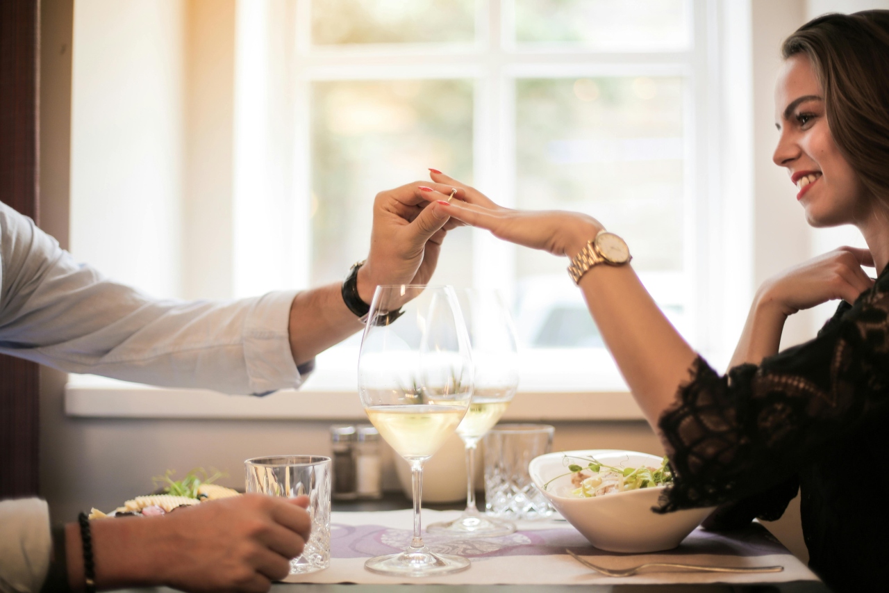 A newly engaged couple enjoying a romantic dinner on a bright sunny day.