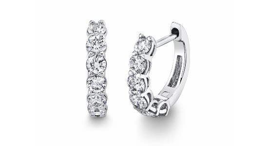 a pair of white gold huggies earrings featuring prong set diamonds