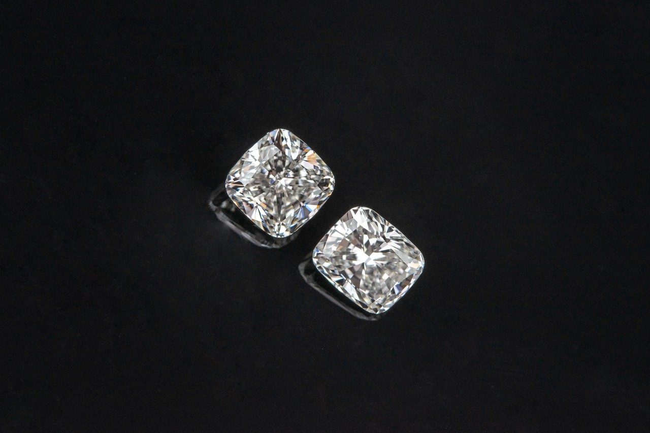 Two cushion cut diamonds on a polished black surface
