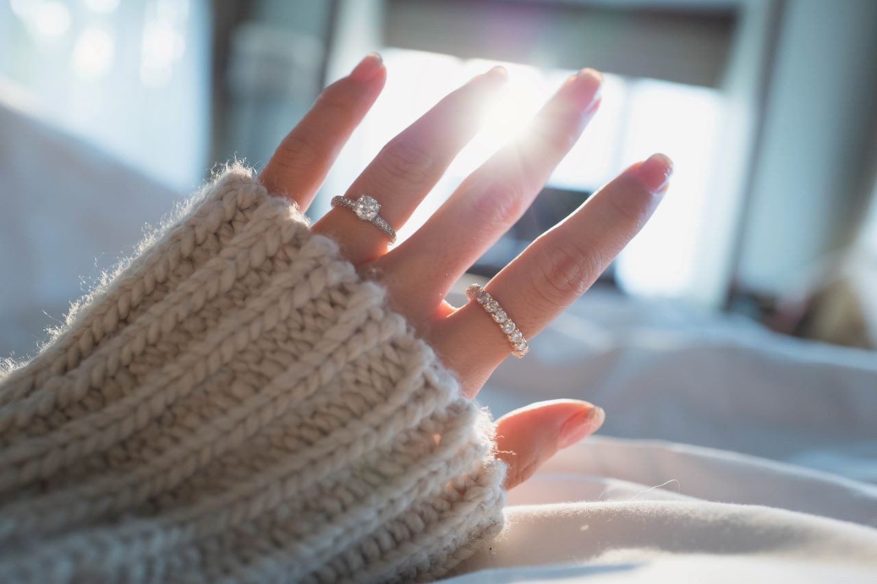 A woman with a side stone diamond engagement ring and diamond eternity band