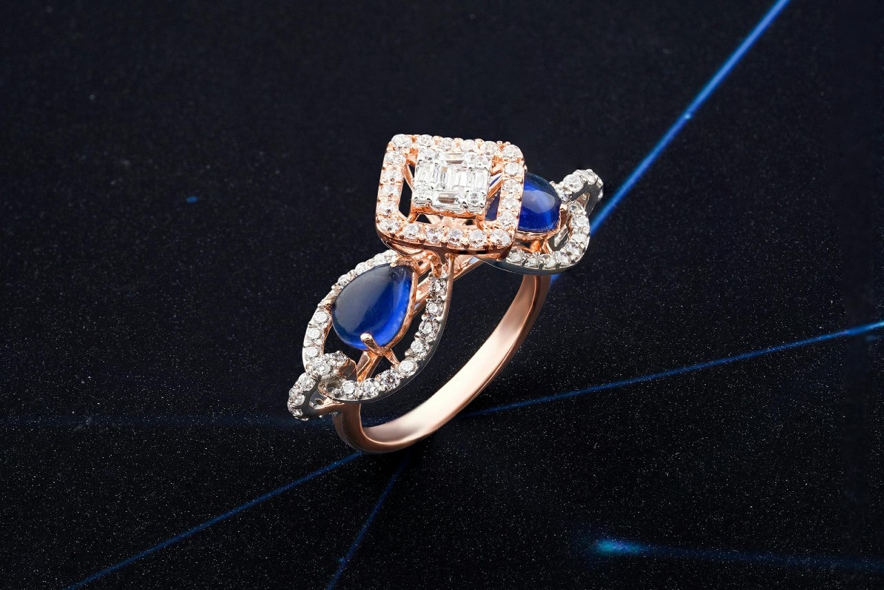 A close-up of a distinctive engagement ring with a princess cut diamond center stone, multiple halos, and sapphire accent stones.