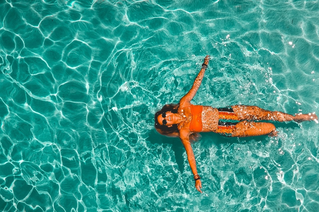 A happy woman swimming in pristine blue water.