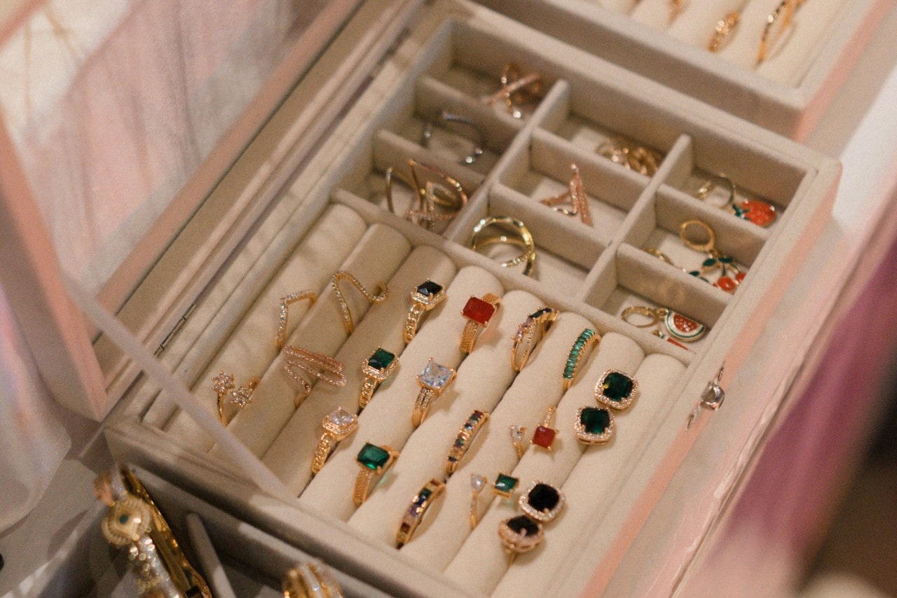 An over-the-top view of an ornate jewelry box with a multitude of diamond and gemstone rings carefully organized inside.