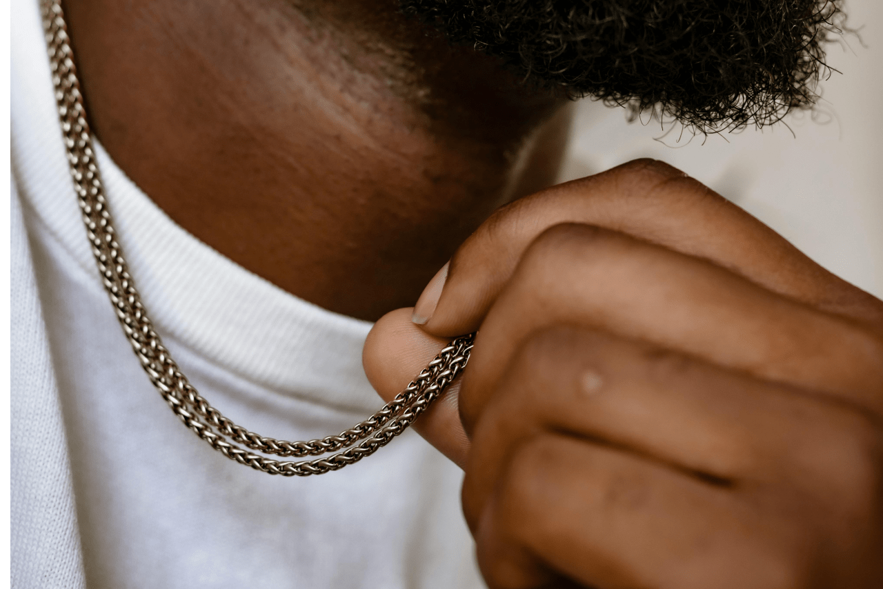 A close-up of a man’s neck adorned with a double chain necklace