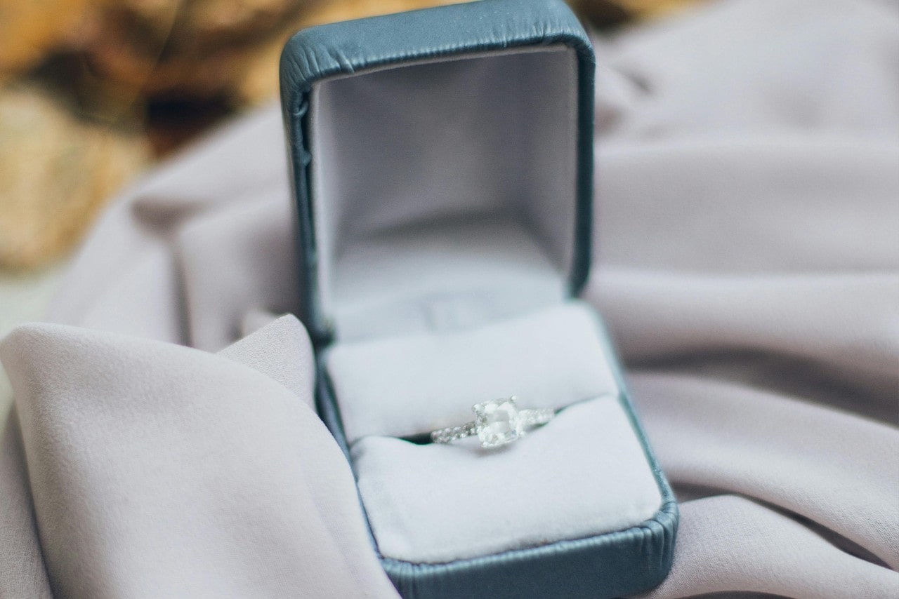 a diamond engagement ring in a light blue ring box