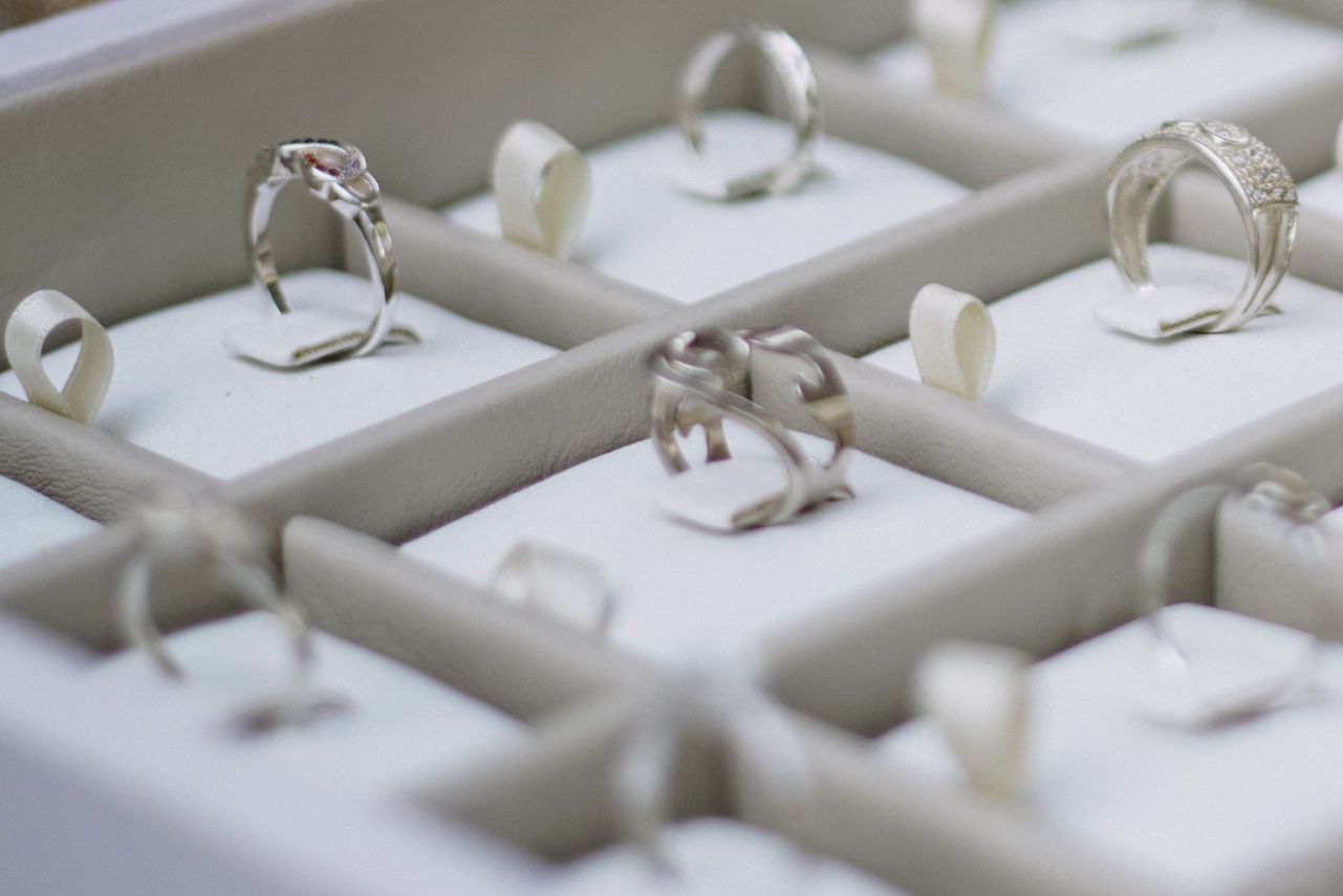 A close-up, angled view of various white gold engagement rings displayed inside individual slots of a padded jewelry tray.