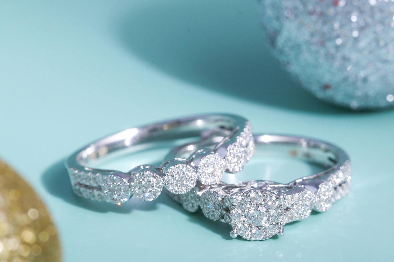 Two diamond-encrusted white gold wedding rings resting stacked together on a light blue surface.