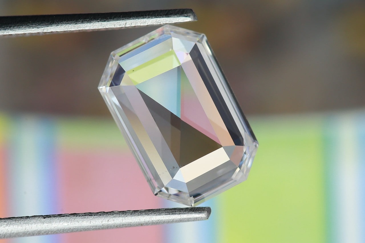 an asscher cut diamond being held up to the camera with tweezers