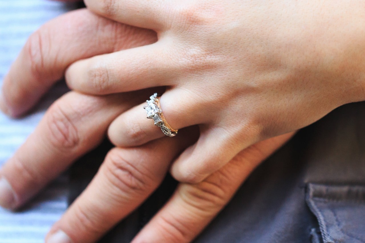 a couple holding hands, the woman wearing a mixed metal diamond engagement ring