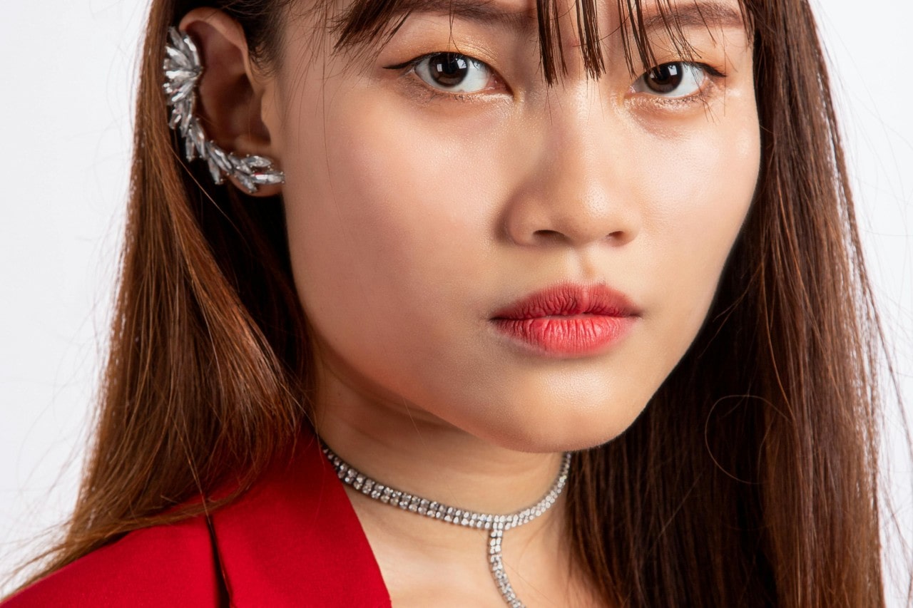 A close-up of a fashionable woman wearing a distinctive diamond ear cuff and diamond lariat necklace.