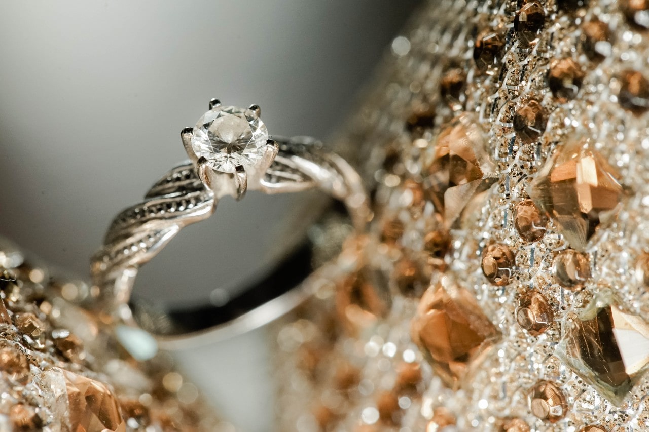 a white gold engagement ring featuring a twisted band surrounded by gems
