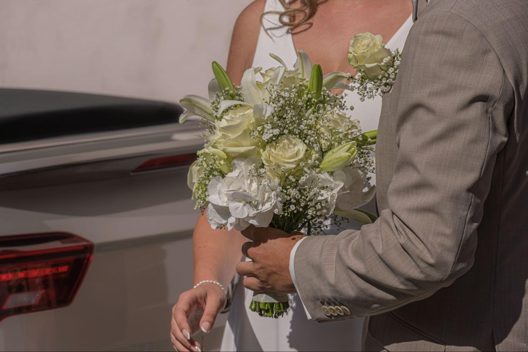 A close up of a groom giving a bride a bouquet.