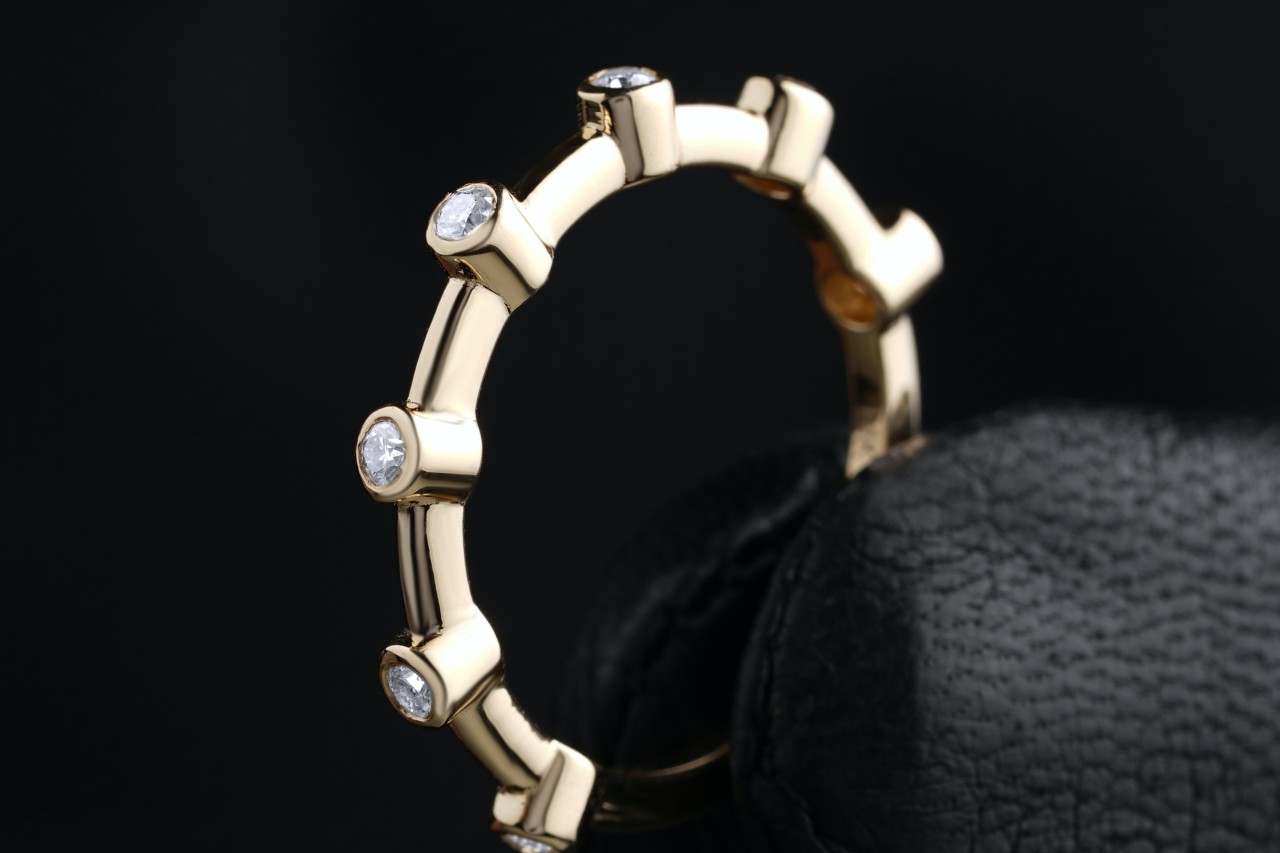 a yellow gold wedding band featuring bezel set diamonds