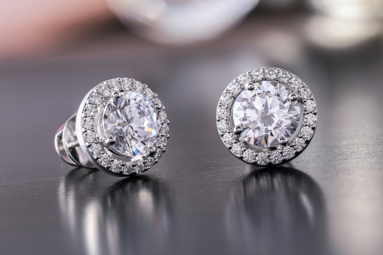 a pair of white gold diamond stud earrings on a metallic surface