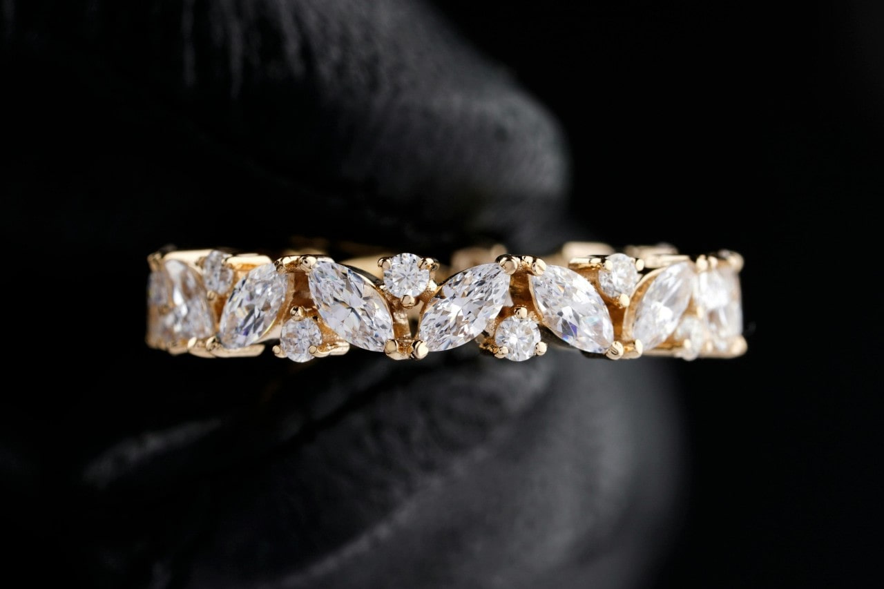 close up image of a a yellow gold wedding band with marquise and round cut diamonds