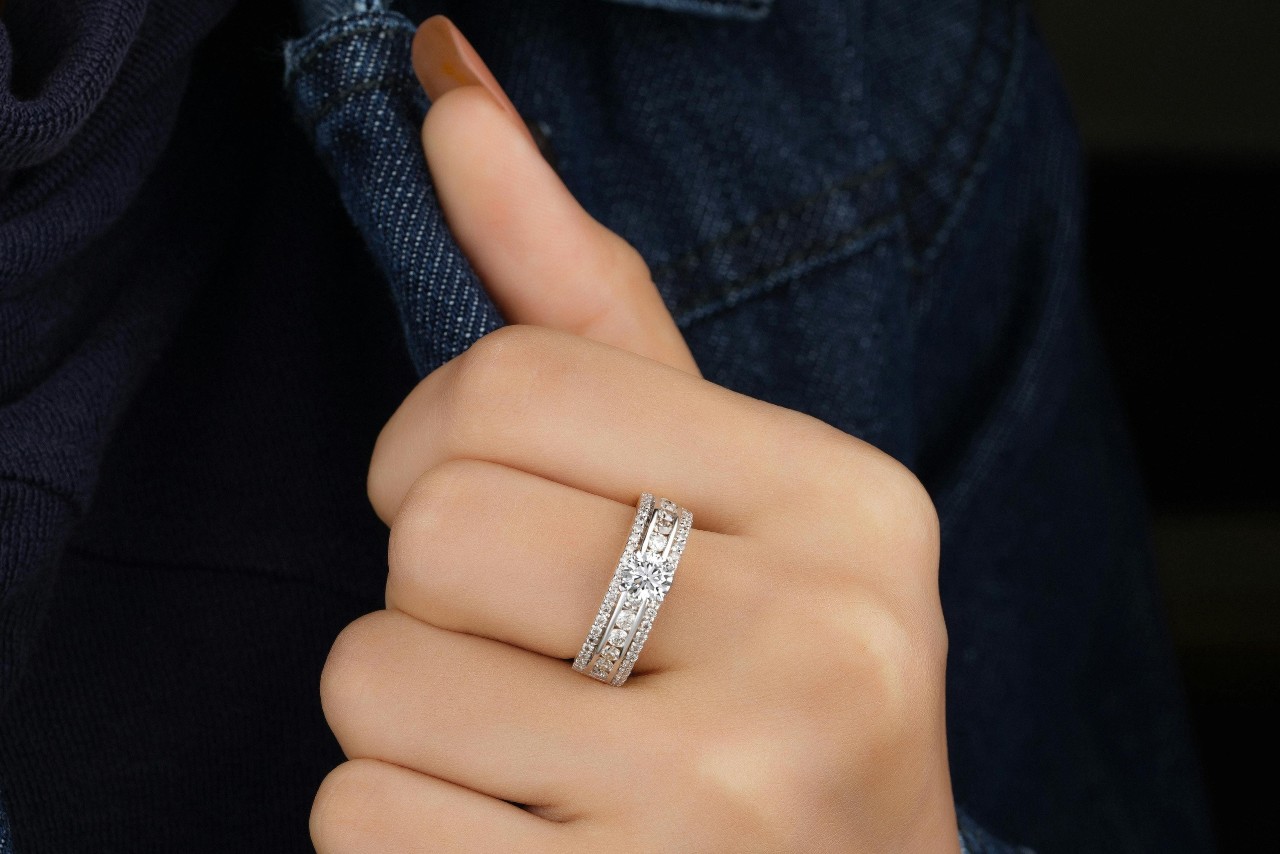 A close-up image of a woman’s hand adorned with a diamond ring with three rows of accent diamonds