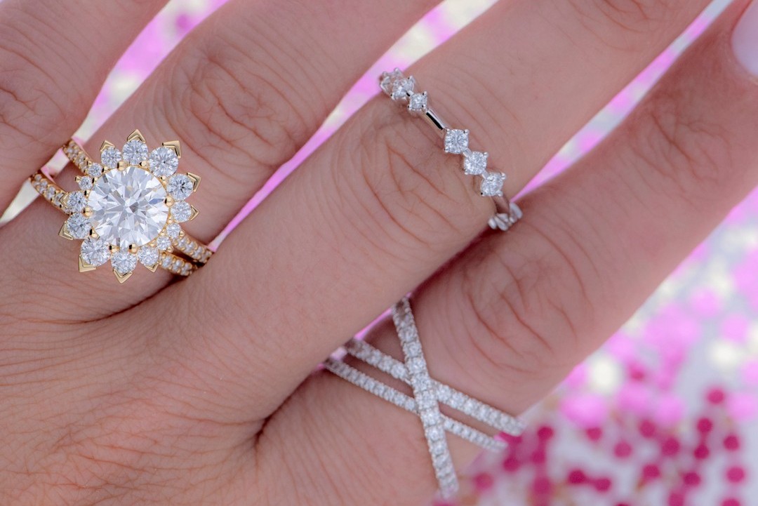 A close-up image of a hand wearing four diamond rings by Hearts On Fire.