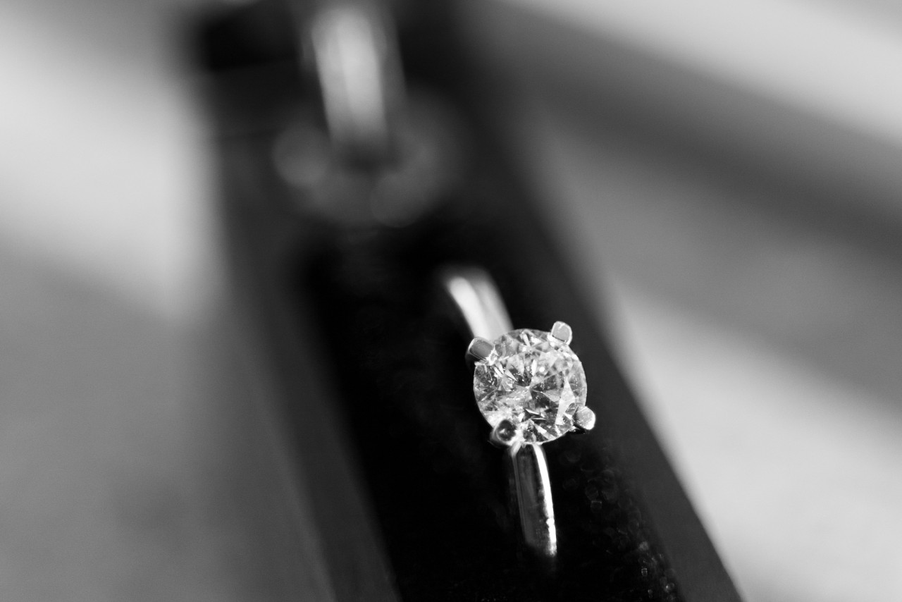 A black and white image of a silver solitaire diamond engagement ring