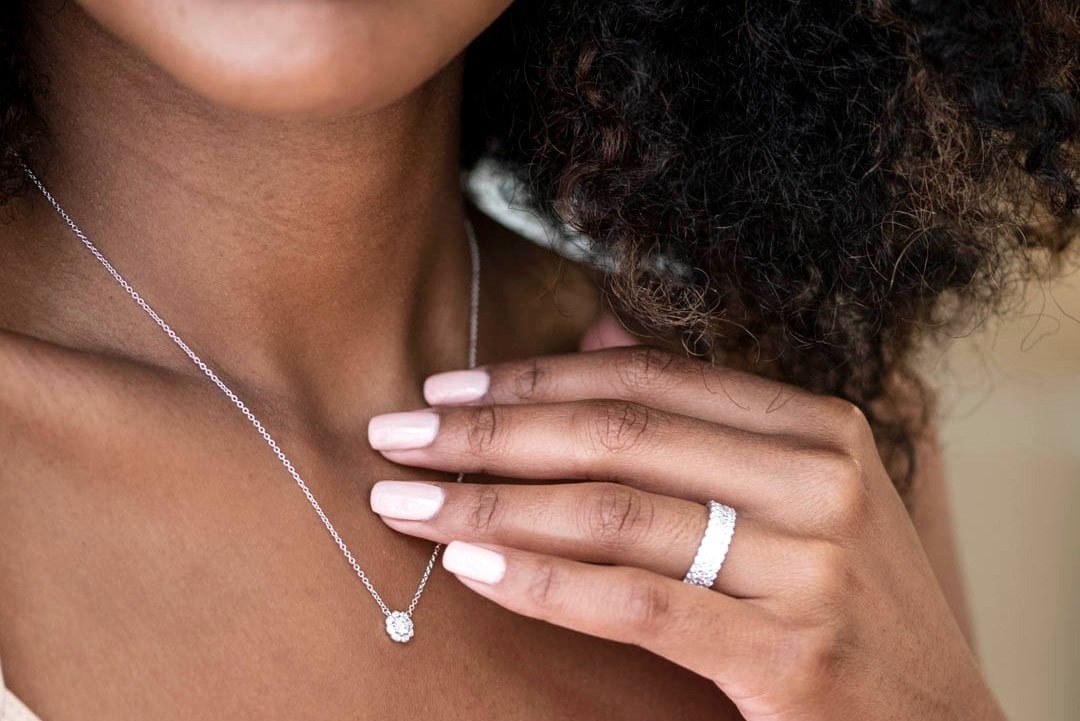 Neckline and hand of a lady wearing diamond jewelry by Hearts on Fire