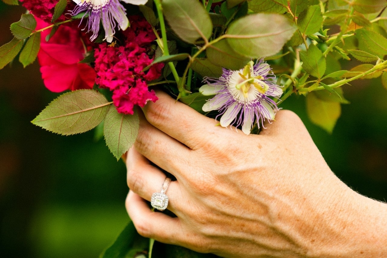 hand holding a bouquet of flowers and wearing a diamond engagement ring