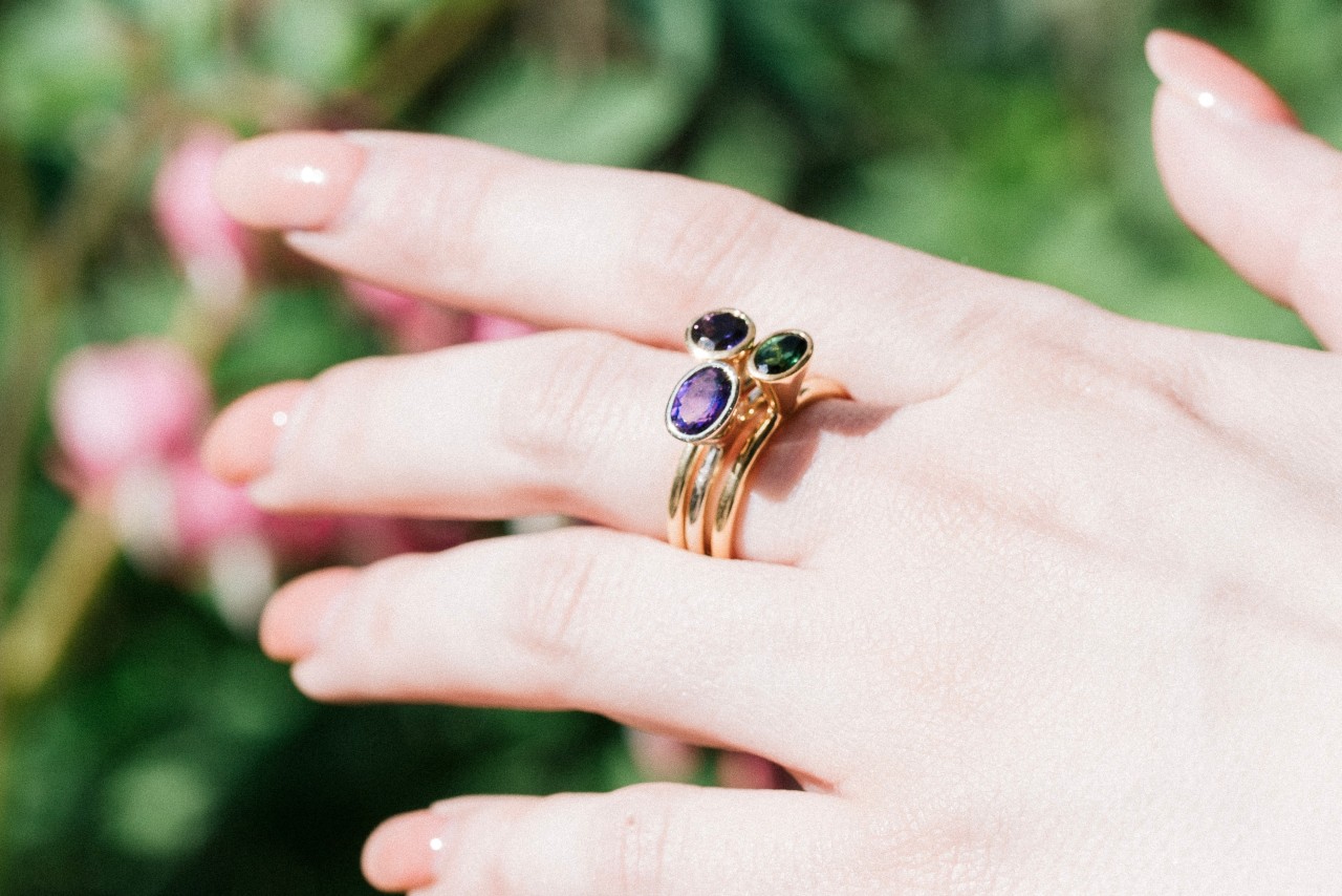 an outstretched hand wearing a stack of yellow gold gemstone rings