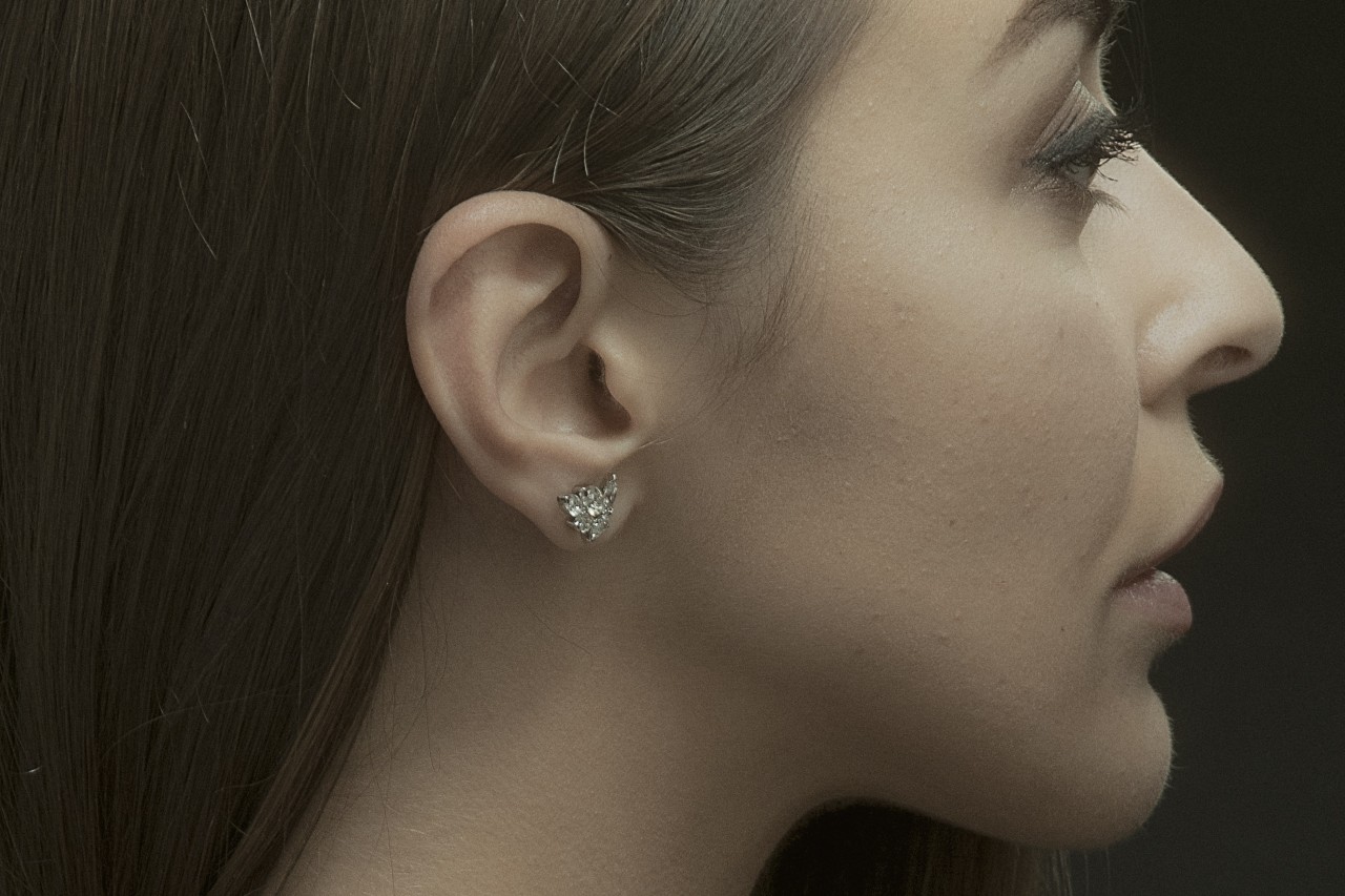view of a woman’s profile wearing a pair of uniquely shaped diamond stud earrings