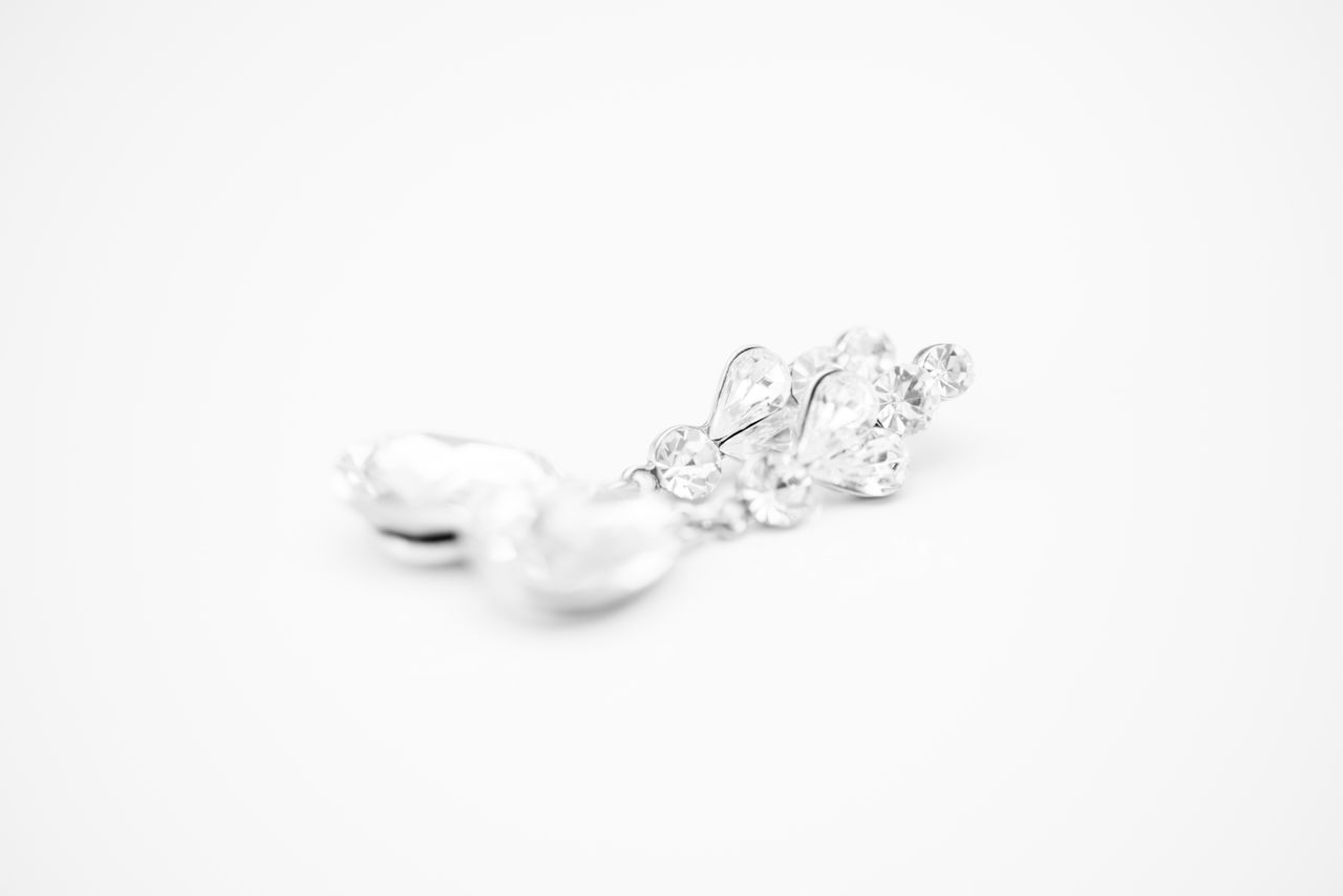 a pair of diamond drop earrings lying on a white surface