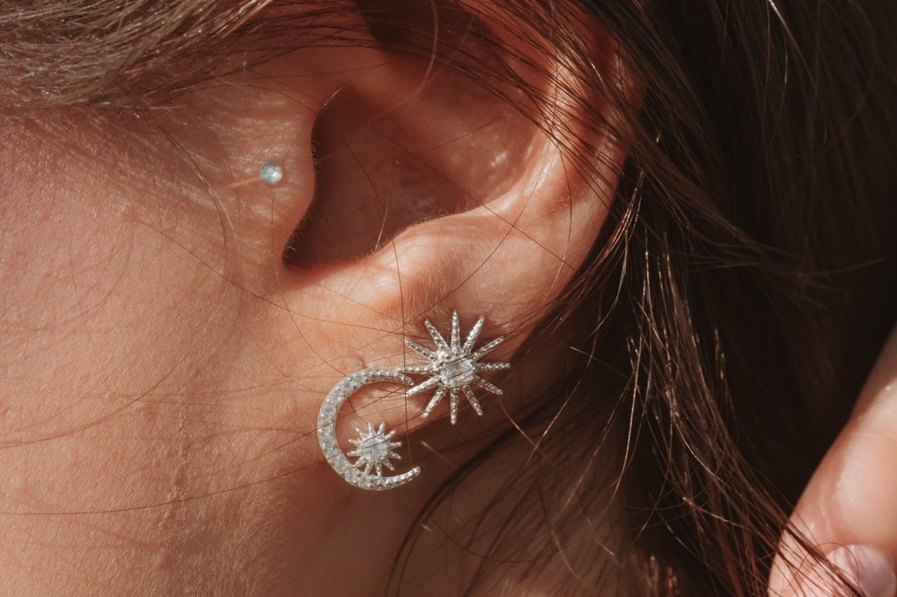 close up image of a person’s ear wearing sun and moon diamond earrings close up image of a person’s ear wearing sun and moon diamond earrings