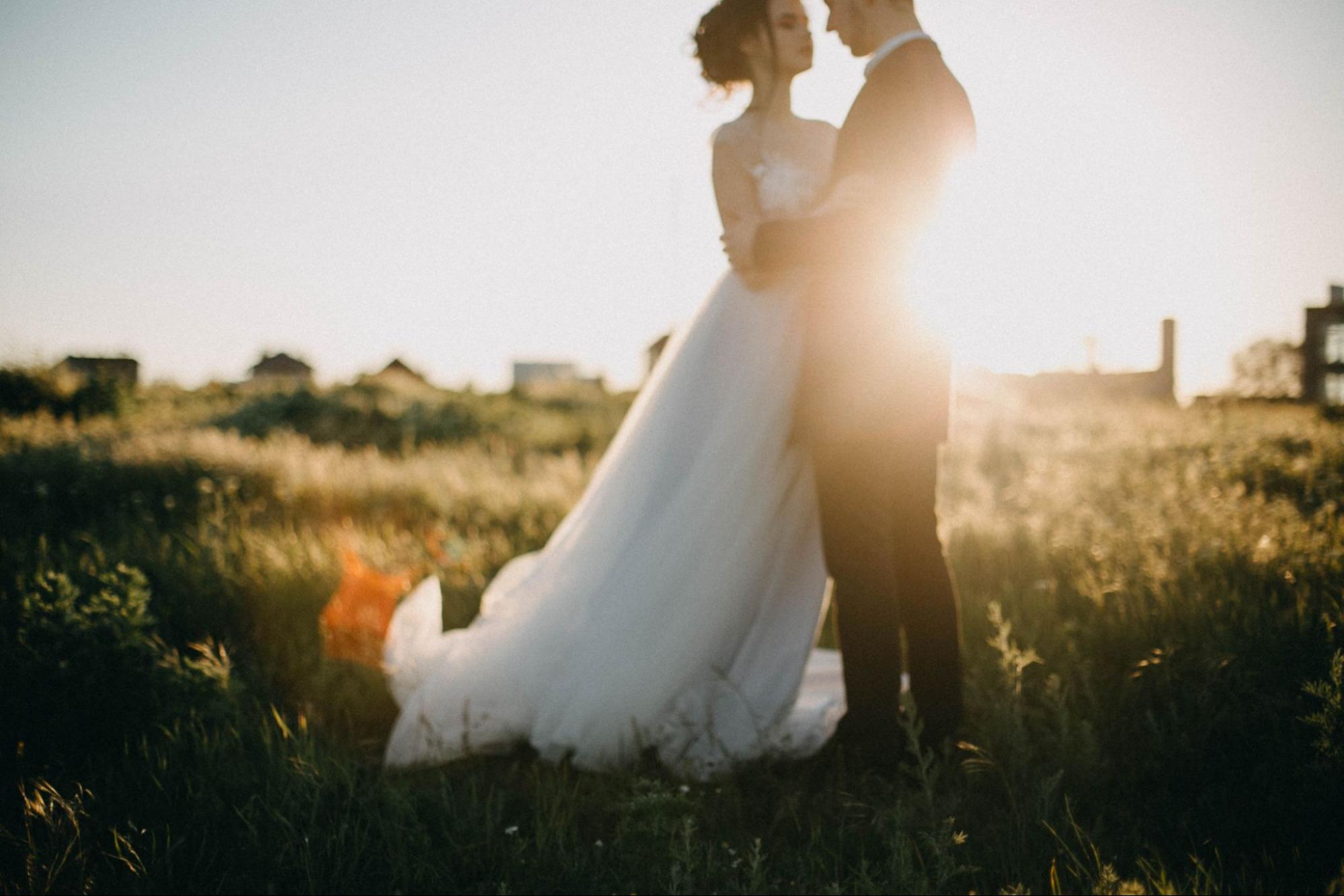 A view of a newlywed bride and groom in each other's arms at sunset. A view of a newlywed bride and groom in each other's arms at sunset.