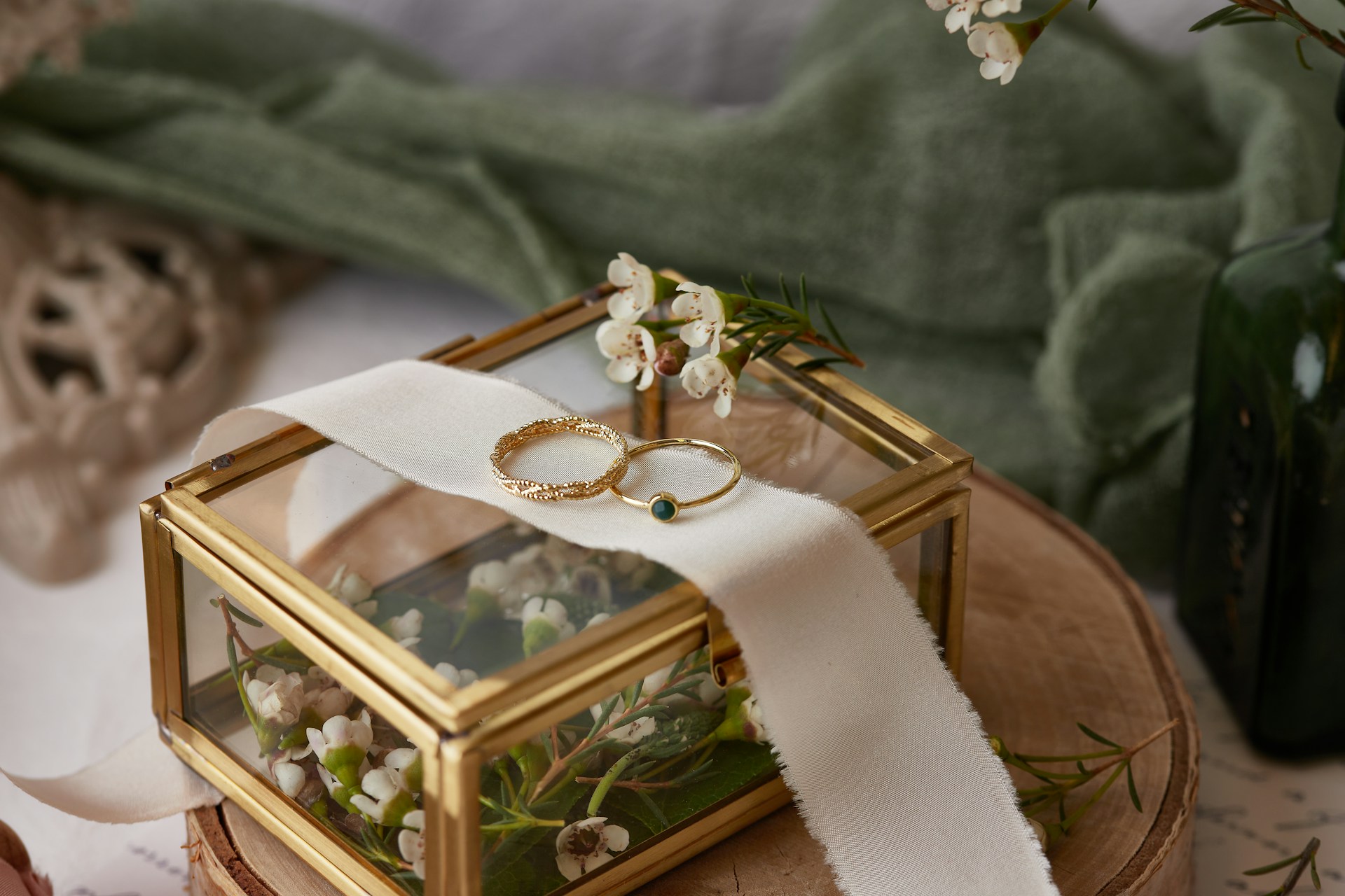 A view of a delicate engagement ring and wedding band displayed atop a glass jewelry box. A view of a delicate engagement ring and wedding band displayed atop a glass jewelry box.