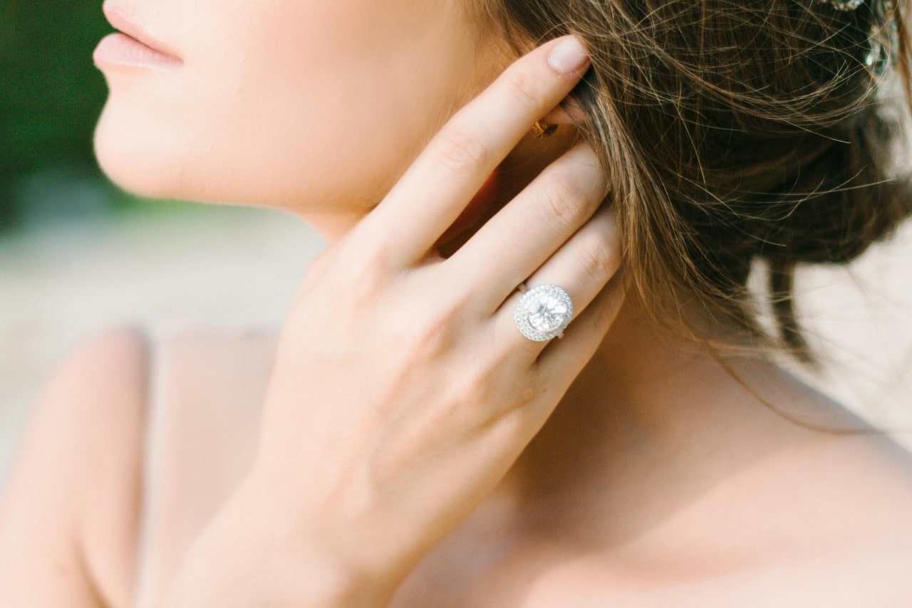 a bride pushing back her hair and wearing a large diamond engagement ring