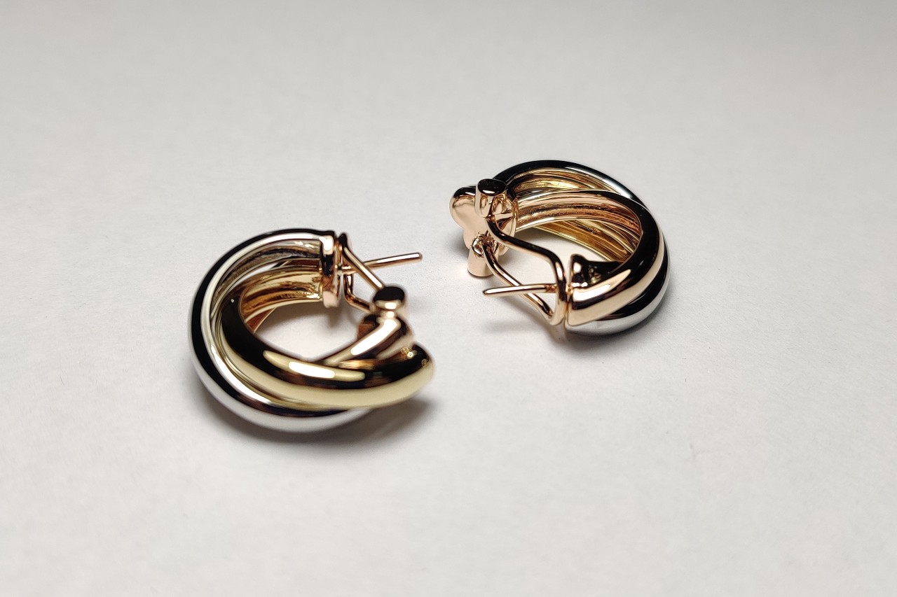 a pair of mixed metal hoop earrings lying on a white surface