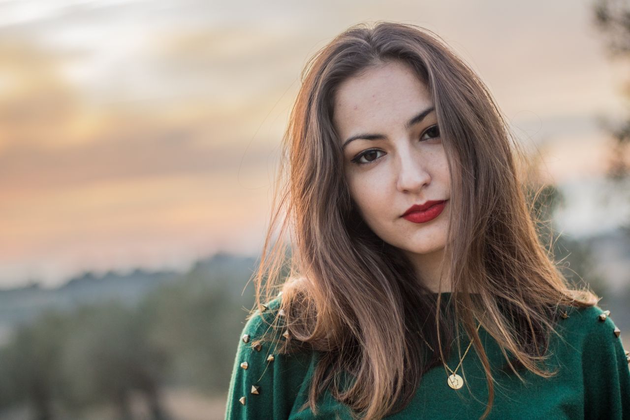 A woman wearing a gold medallion necklace at sunset