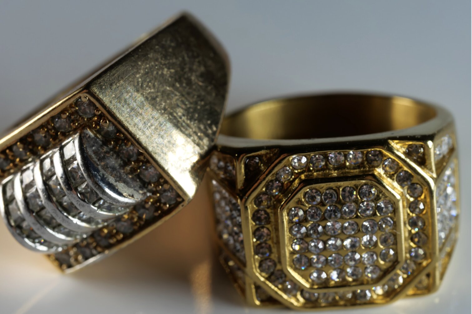 Two thick golden rings with diamond detailing lying next to one another.