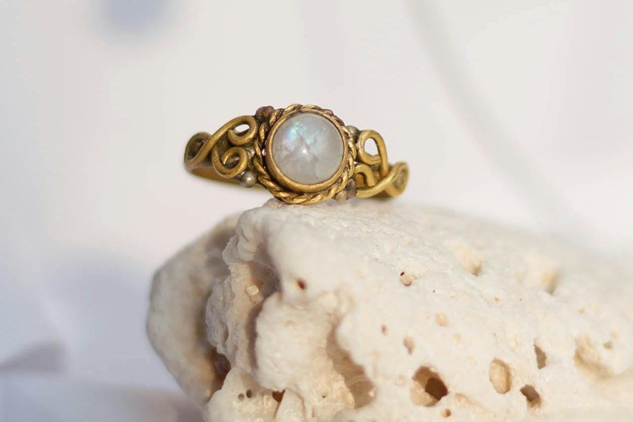 A yellow gold fashion ring with a mother of pearl centerpiece on a white stone.