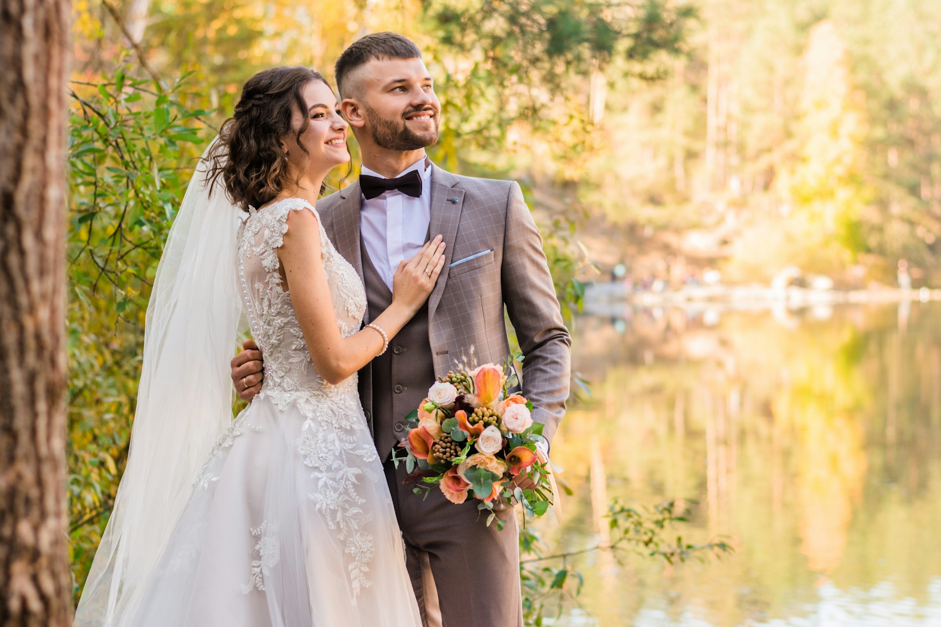 a bride and groom standing by a lake a bride and groom standing by a lake