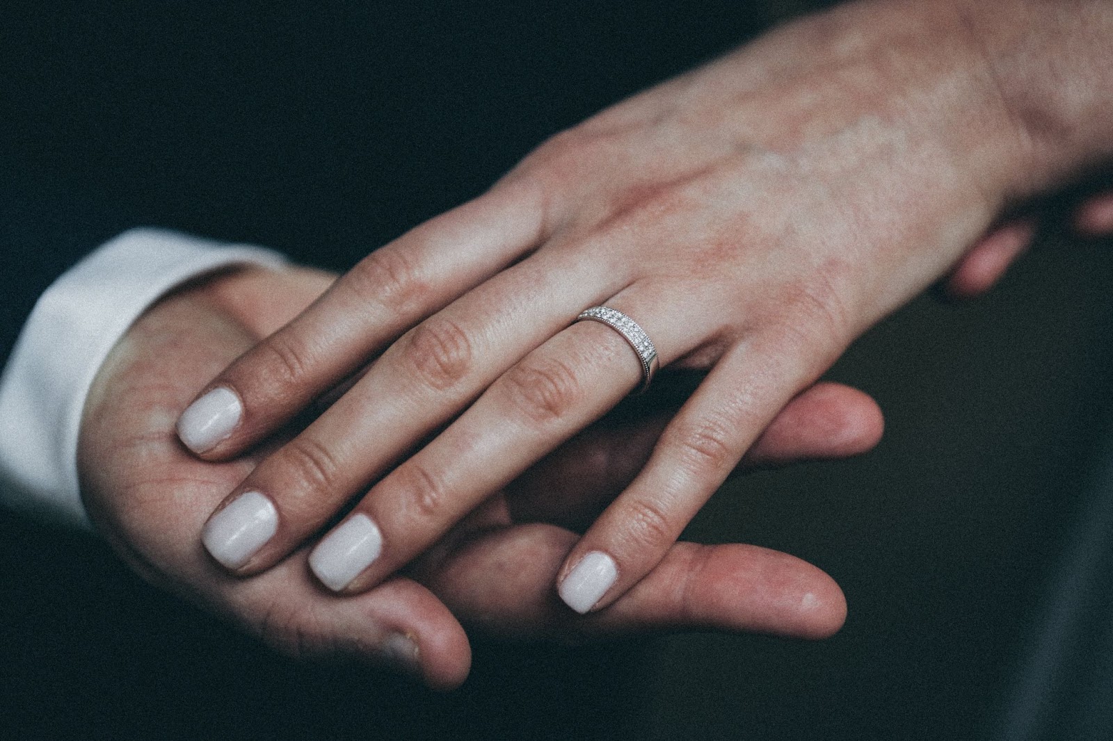 Two people holding hands, with the lady's wearing a diamond wedding band