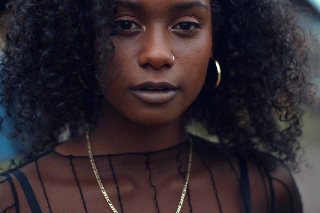 A woman in a sheer black top and a chain necklace. A woman in a sheer black top and a chain necklace.