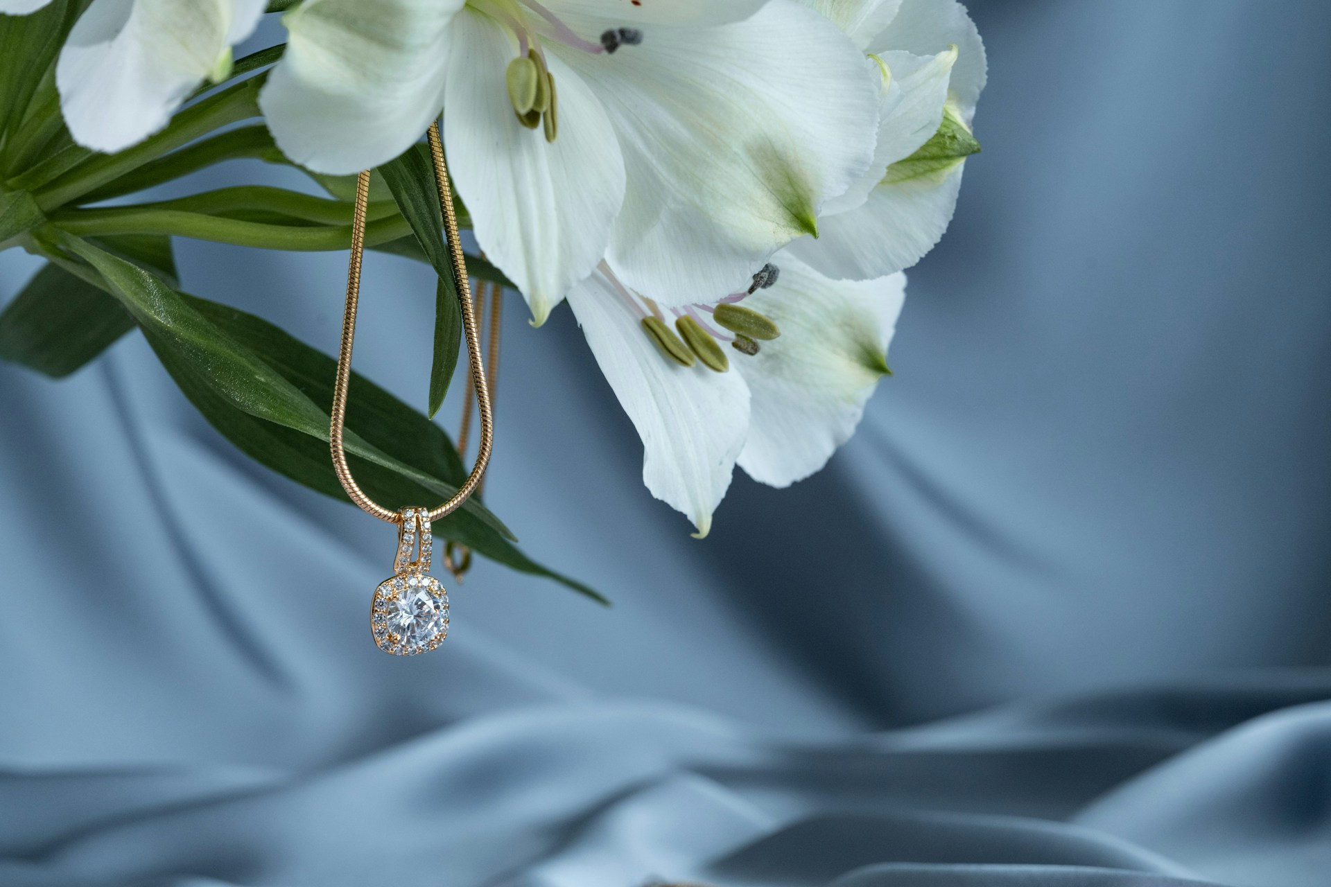 a yellow gold diamond pendant necklace hanging off of a bouquet of flowers a yellow gold diamond pendant necklace hanging off of a bouquet of flowers