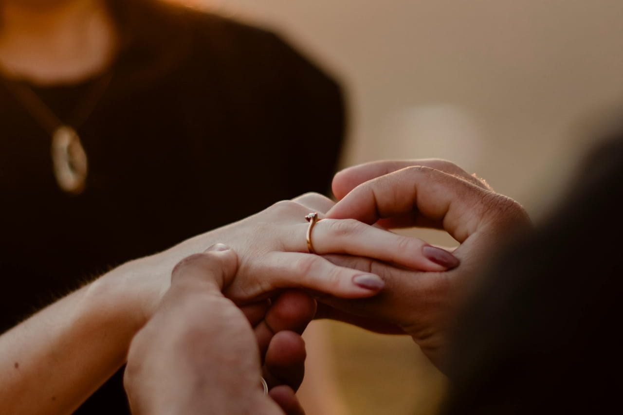 a man's hands placing engagement ring on a woman's finger a man's hands placing engagement ring on a woman's finger