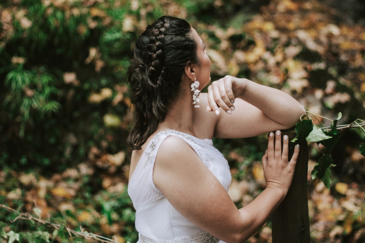 The side profile of a woman with braided hair wearing statement white floral drop earrings. The side profile of a woman with braided hair wearing statement white floral drop earrings.