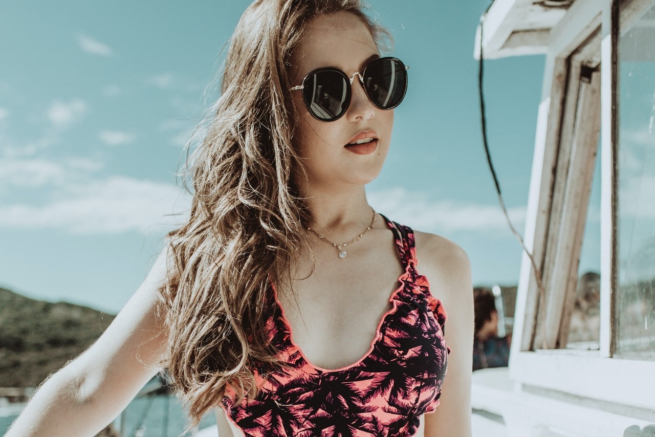 lady wearing sunglasses, summer clothes, and fine jewelry standing on a boat