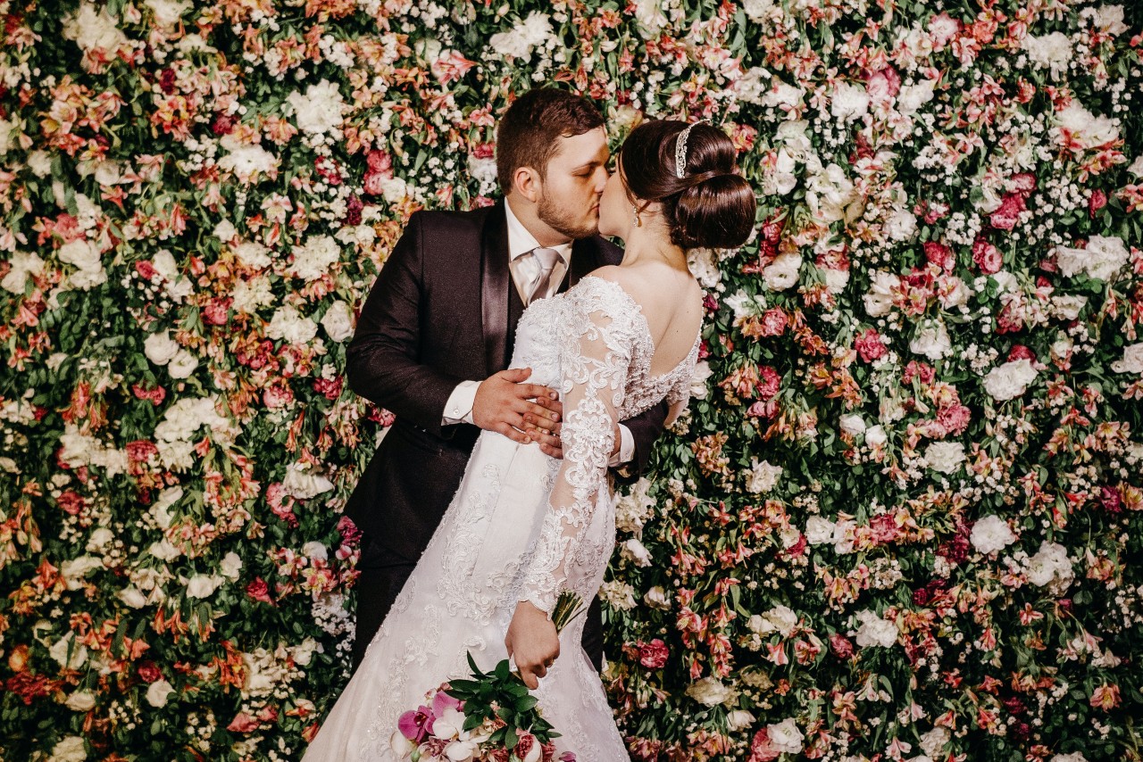 a bride and groom kissing with a floral background
